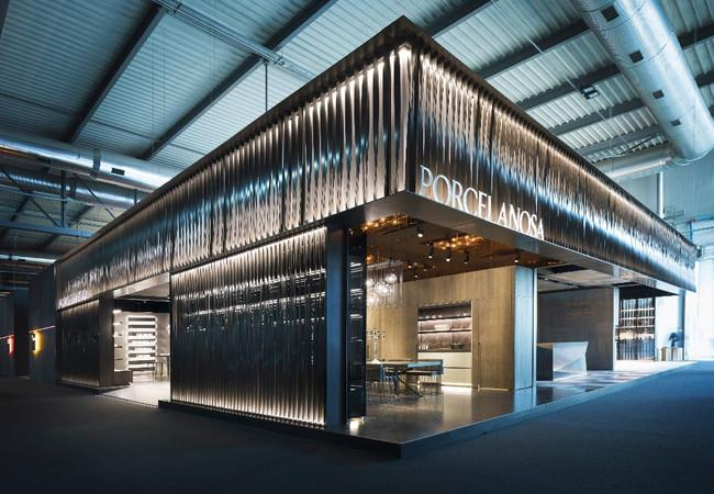 A dramatic lit exhibition stand with a rippled metal facade